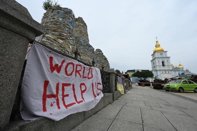 A banner reading "World help us" displayed on the covered and protected Monument to Princess Olga in Kyiv (Ukraine)